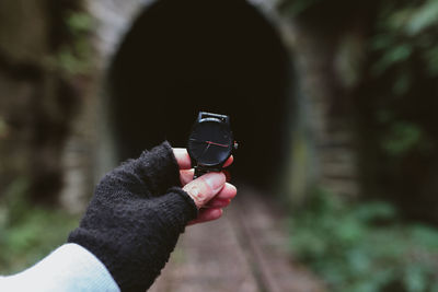 Cropped image of person holding wristwatch by tunnel