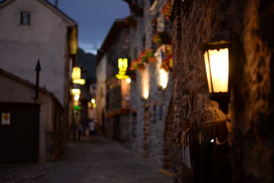 Illuminated street amidst buildings at night