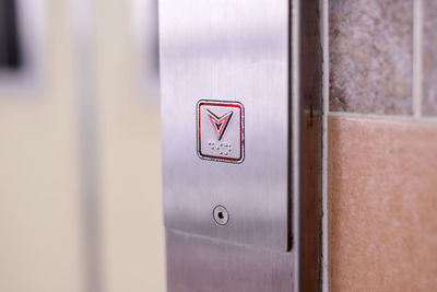 Close-up of down arrow elevator button on wall