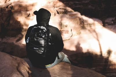 Rear view of man sitting on rock