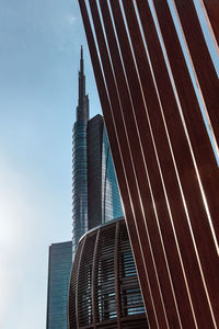 A skyscraper on the background framed by diagonal striped wooden structure on the foreground.