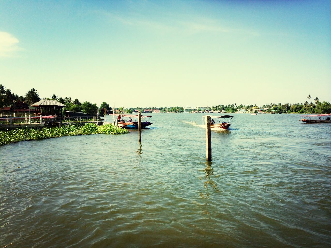 water, nautical vessel, building exterior, built structure, transportation, architecture, boat, mode of transport, waterfront, sky, tree, river, moored, rippled, incidental people, day, clear sky, canal, outdoors, nature