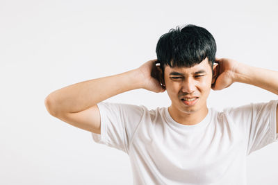 Portrait of young man exercising against white background