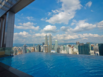 City at waterfront against cloudy sky