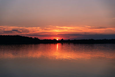 Sun setting behind the trees on horizon of a lake in ontario, canada.