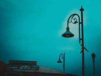 Low angle view of illuminated street light against blue sky