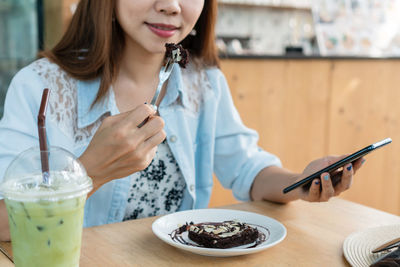 Midsection of woman holding smart phone on table