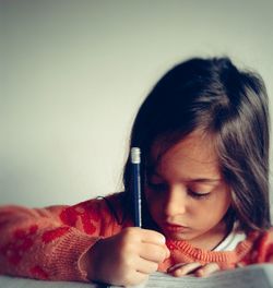 Girl studying against gray wall