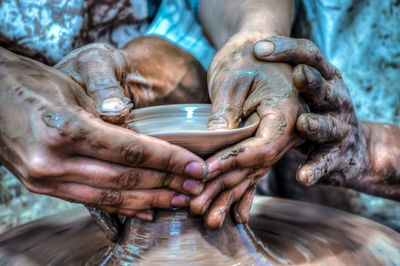 Close-up of man teaching pottery to woman