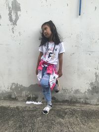 Portrait of smiling young woman against wall