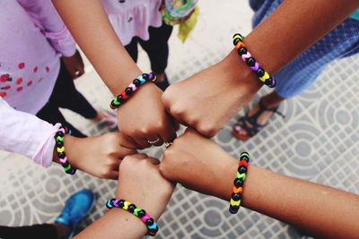 High angle view of friends wearing bracelets bumping fist