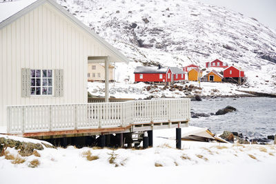 Houses by snow covered house against mountain