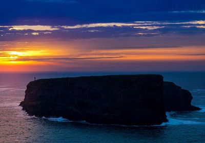 Rock formation on sea against sky during sunset