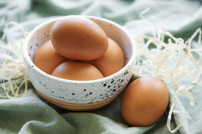 Bowl of fresh brown eggs on concrete background