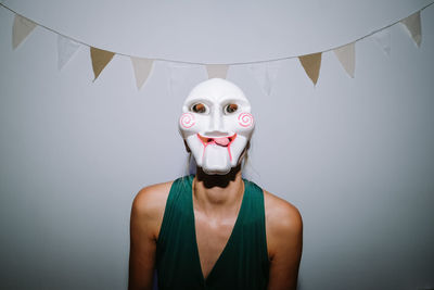 Portrait of person wearing mask standing against wall covered