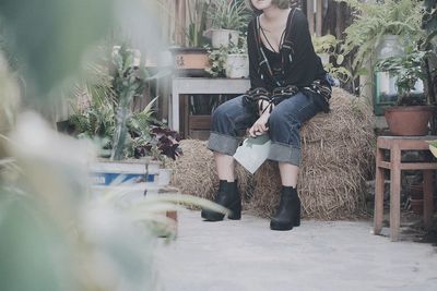 Woman sitting on hay bale against building