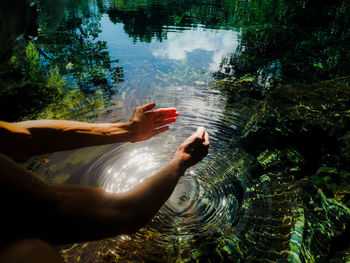 Cropped hands of woman gesturing over lake