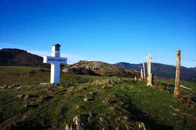 Scenic view of cross against clear blue sky