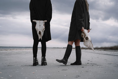 Friends walking on beach against sky