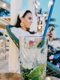 Selective focus of refreshing cocktail on table in bar and young woman in background.