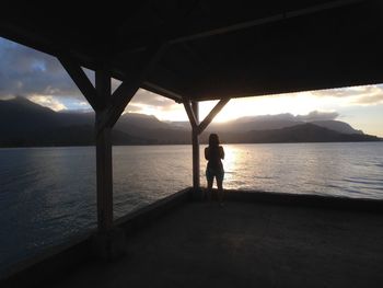 Silhouette man standing on sea shore against sky