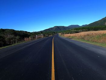 Empty road against clear blue sky