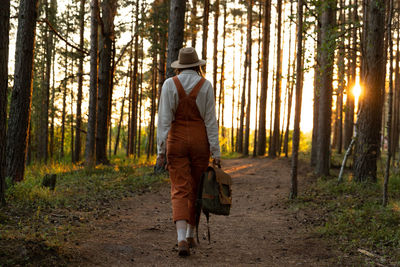 Woman botanist with backpack on ecological hiking trail in forest. naturalist exploring ecotourism