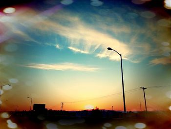 Illuminated street light in city against sky