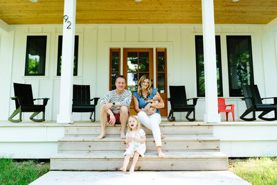 Straight on portrait of a family of four sitting on porch stairs