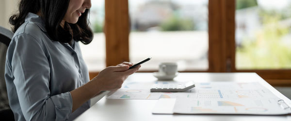 Midsection of businesswoman working at desk in office