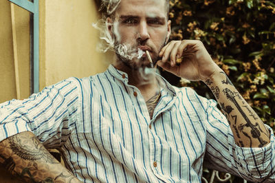 Portrait of young man smoking cigarette outdoors