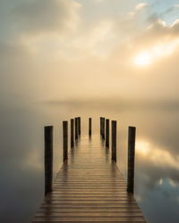 Wooden jetty in sea against sky