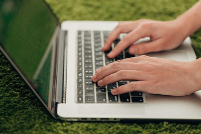 Midsection of woman using laptop on grass at park