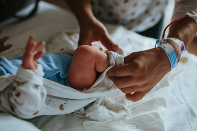 Midsection of woman with newborn son lying on bed in hospital