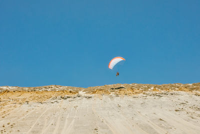 Young man paragliding during summer off cliffs in baja, mexico.