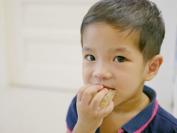 Close-up portrait of cute boy eating food at home