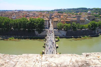 Bridge over river by buildings in city against sky