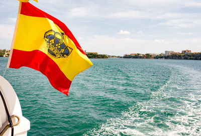 Red flag in sea against sky