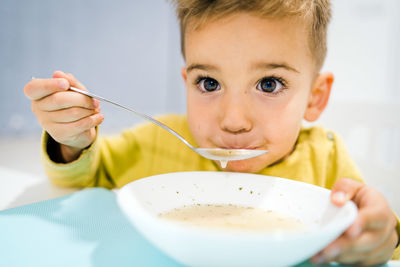 Close-up portrait of cute boy having food at home