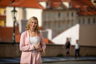 Portrait of woman standing against building in city