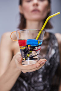 Midsection of young woman holding drinking glass with plastics