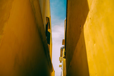 Low angle view of yellow buildings against blue sky