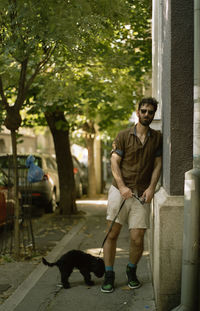 Full length of man with dog standing on footpath