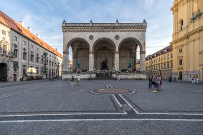 People on street by buildings against sky in city