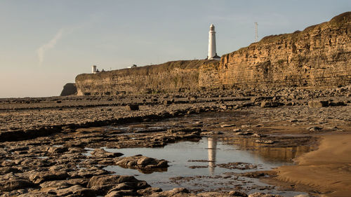 View of lighthouse on a cliff against the sky