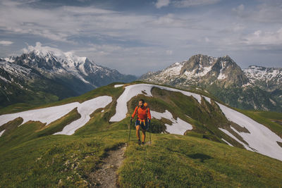 Rear view of man standing on mountain against sky