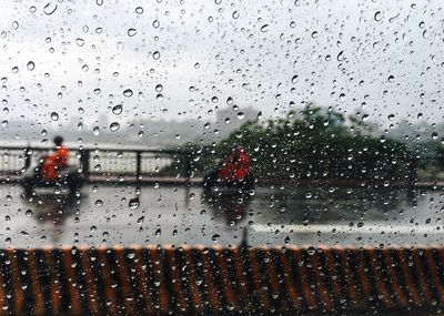 Raindrops on windshield seen through wet window in rainy season