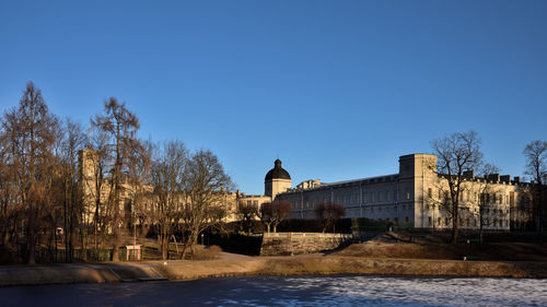 River amidst buildings against clear blue sky