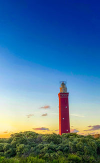Lighthouse standing on the dutch coast with a dramatic. and colorful dusk or dawn sky behind it
