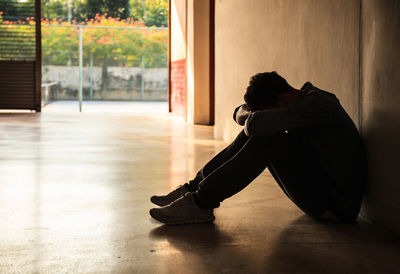 Side view of depressed man sitting on floor